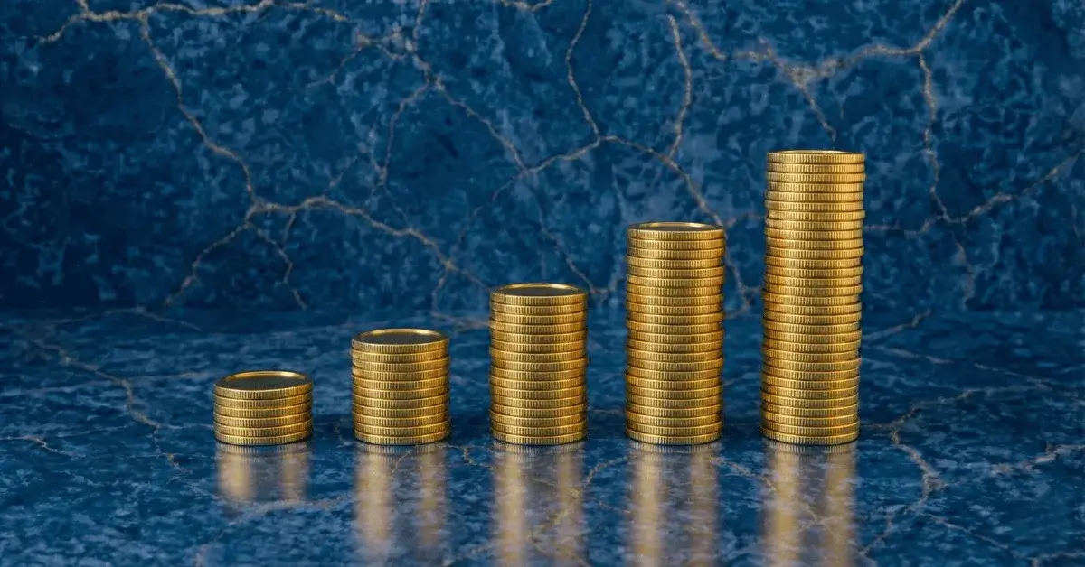 Five towers of golden coins stacking progressively higher, set against a deep blue marble background with golden veins, symbolizing the growth of wealth through investing.