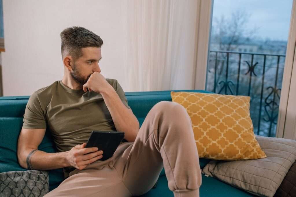 man sitting on couch thinking about affirmations against his anxiety