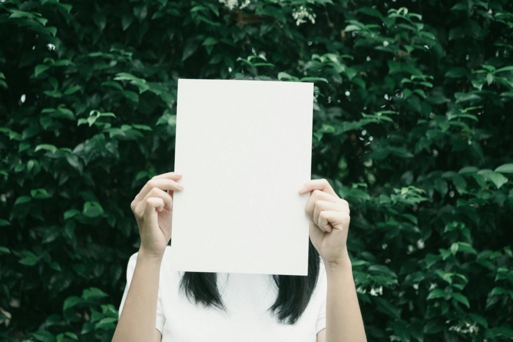 Woman holding a piece of paper in front of her face, symbolizing the enneagram personality test.