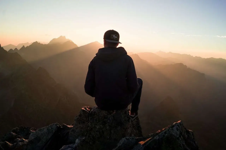 Man sitting on mountain hopeful outlook